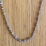 Detalle de la cadena calaveras de plata con eslabones entrelazados, perfecta para expresar tu estilo único